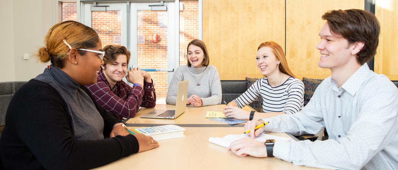 Students talking around a table in a the Adler Journalism Building